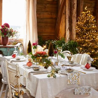 Christmas dining table, laid out table settings, white table cloth and chairs, Christmas tree and table garland
