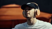 Beyerdynamic Aventho Y lifestyle shot, peach coloured headphones on man with cap