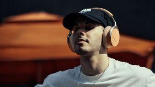 Beyerdynamic Aventho Y lifestyle shot, peach coloured headphones on man with cap