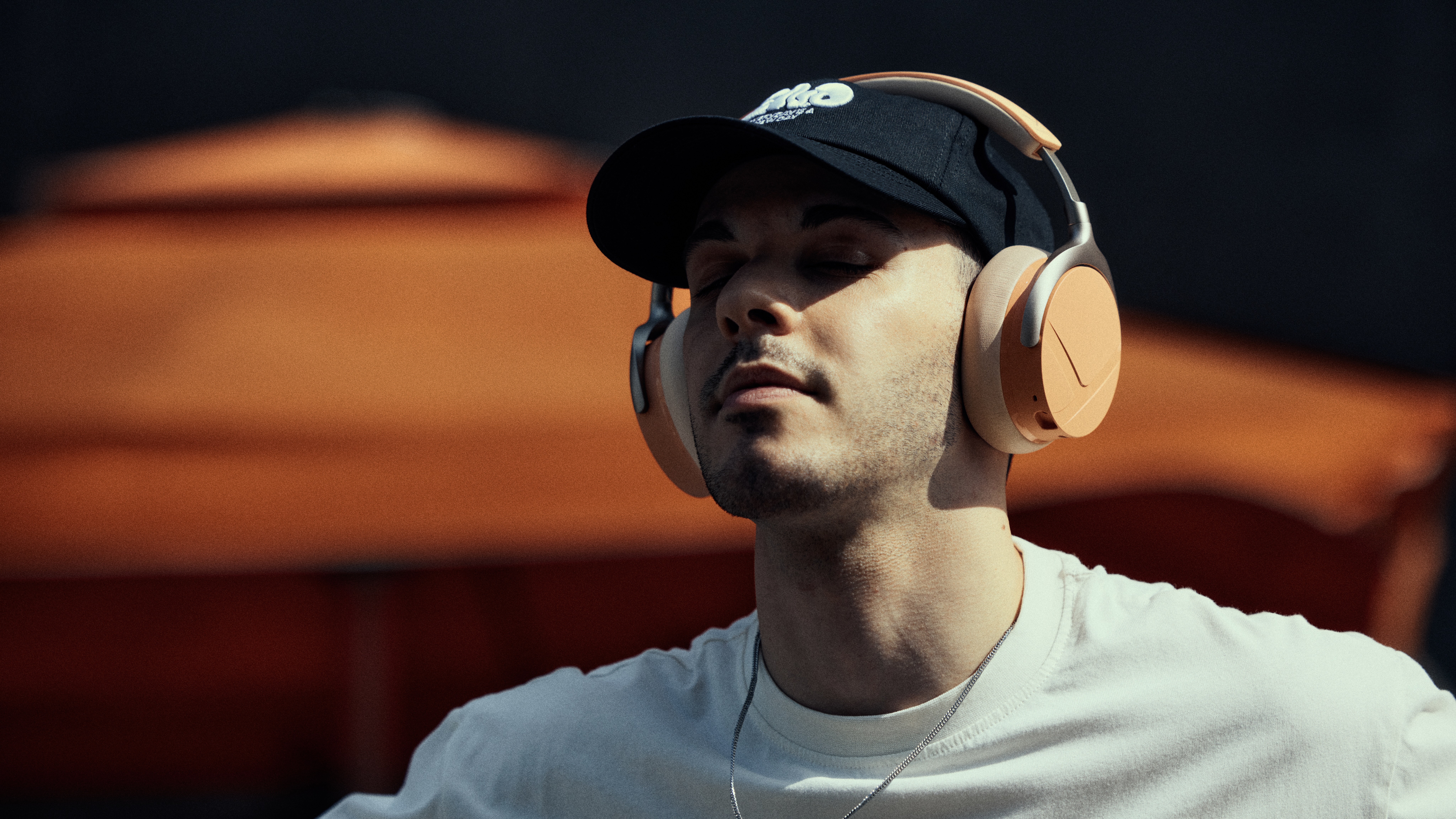 Beyerdynamic Aventho Y lifestyle shot, peach coloured headphones on man with cap