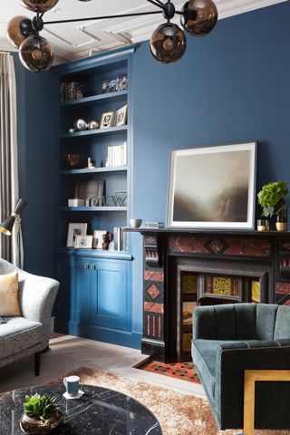 Victorian fireplace dressed with artwork and framed by deep blue wall