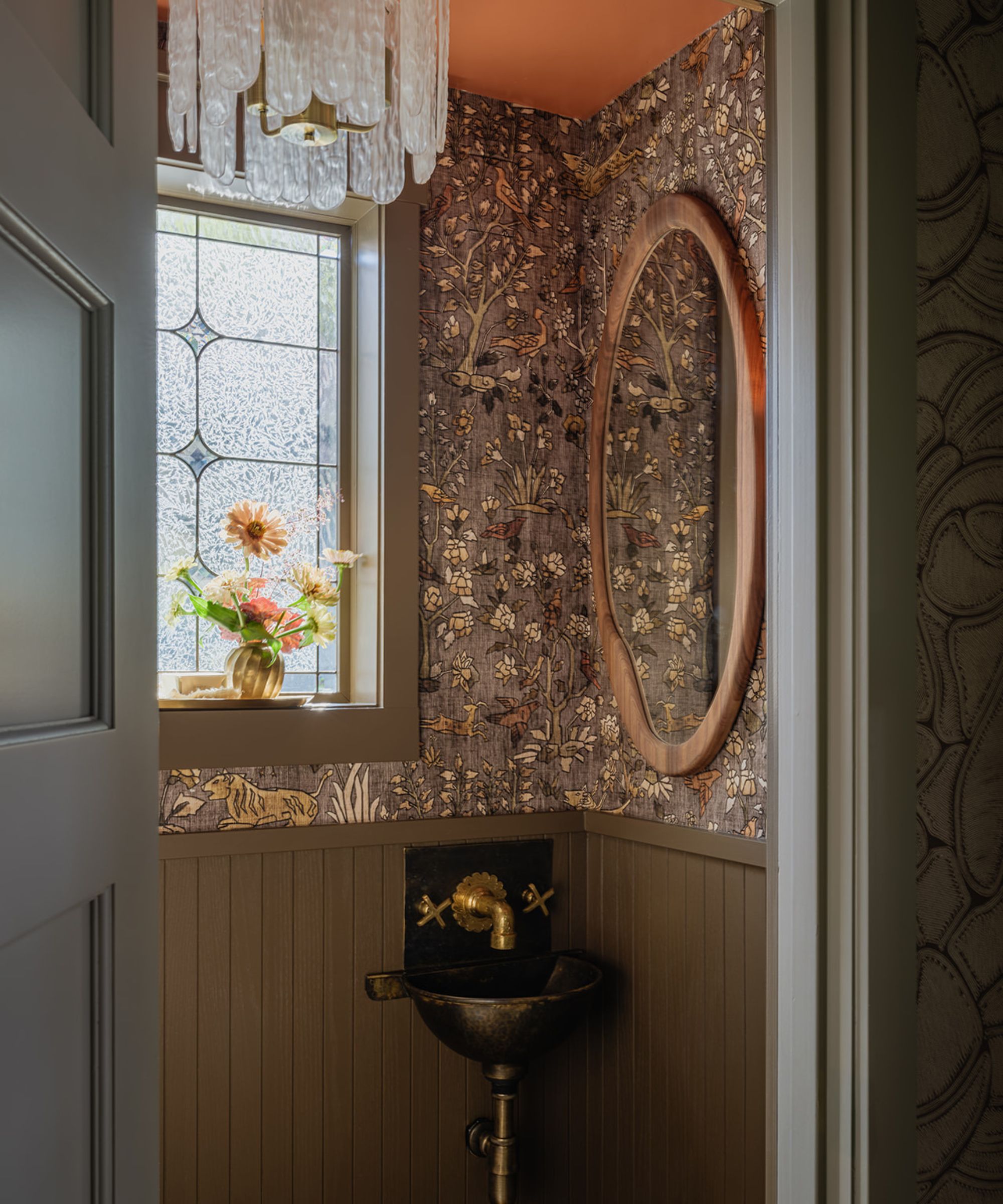 A powder room decorated with green wall paneling and animal wallpaper