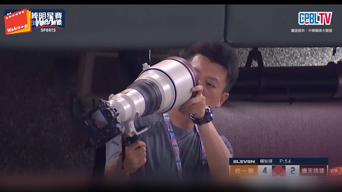 Photographer checks lens after baseball hits it