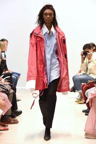 Model wearing a pink trenchcoat on a catwalk