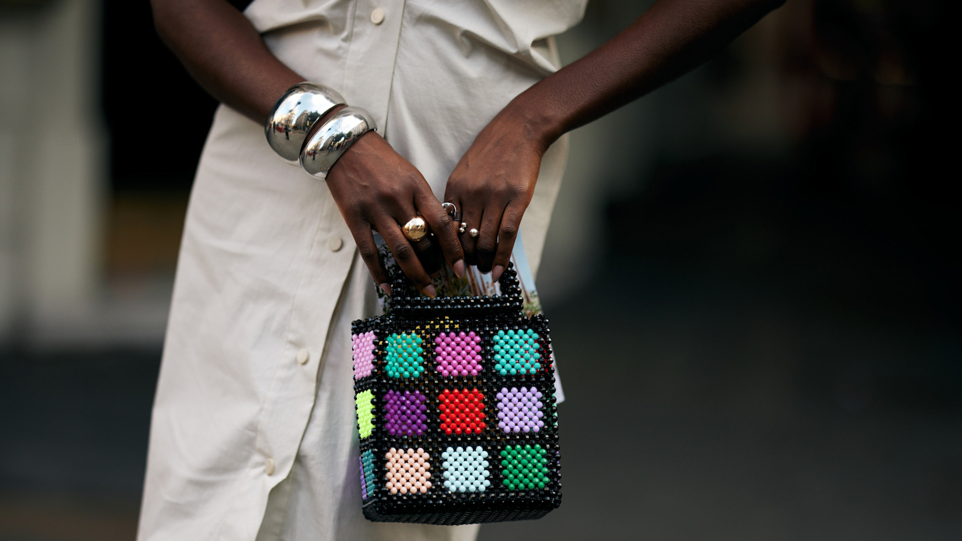 woman wearing silver bangles carrying multicolored beaded bag 