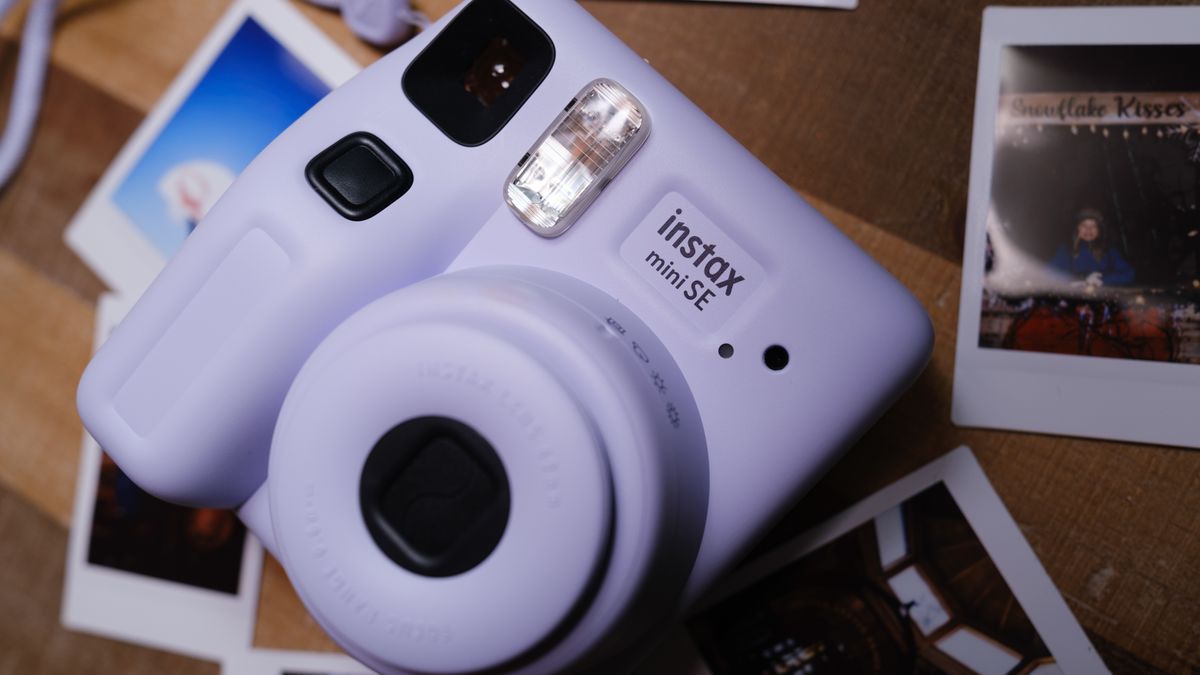 The Fujifilm Instax Mini SE sits on a table with instant film pictures