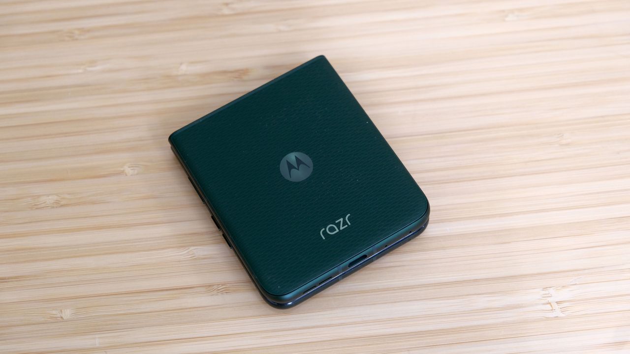 The Motorola Razr Plus 2026 in the hand and on a wooden table