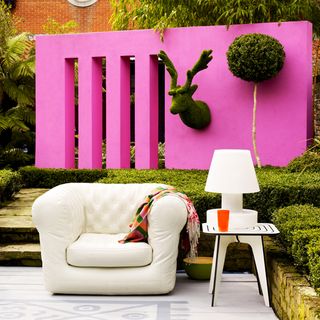 garden with pink garden wall and white arm chair with cushions