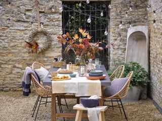Outside dining autumnal decoration, fall wreath and rattan chairs