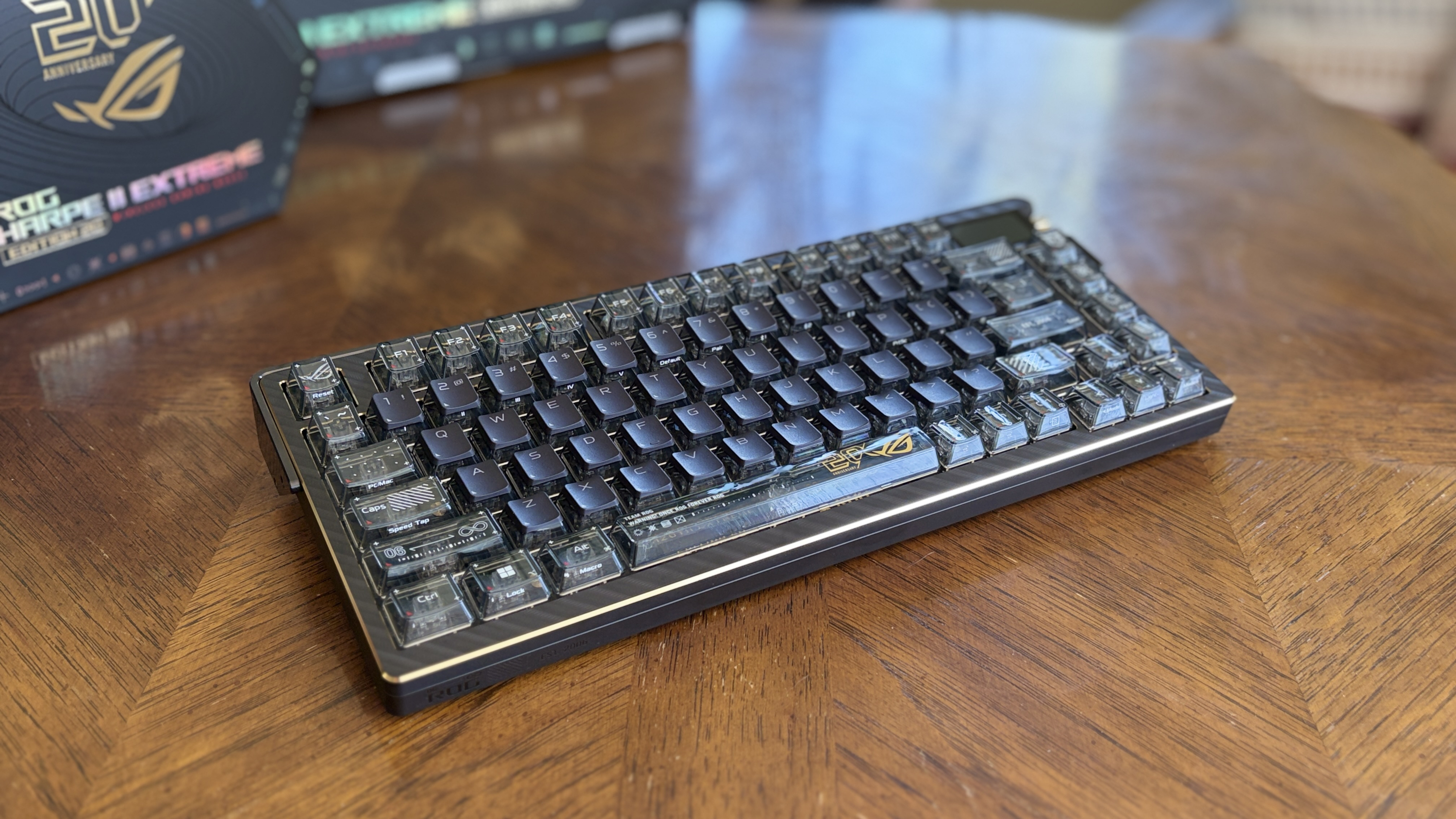 A compact ASUS ROG Azoth Extreme Edition 20 mechanical keyboard with translucent keycaps on a wooden table.