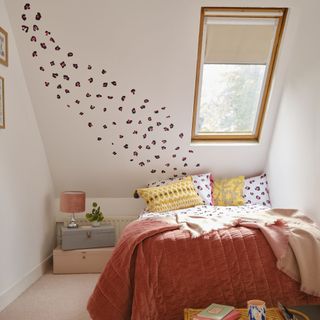 Attic room with white walls, red bed and skylight window