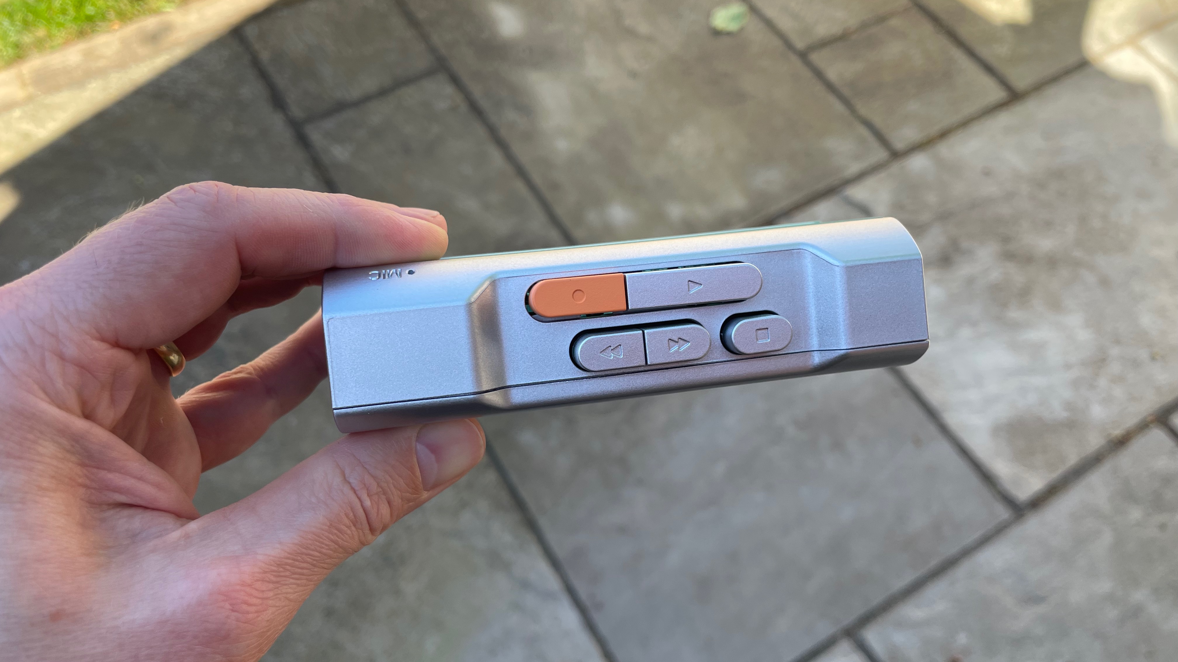 The Gadhouse Miko cassette player held in a garden, showing its top-mounted button controls.