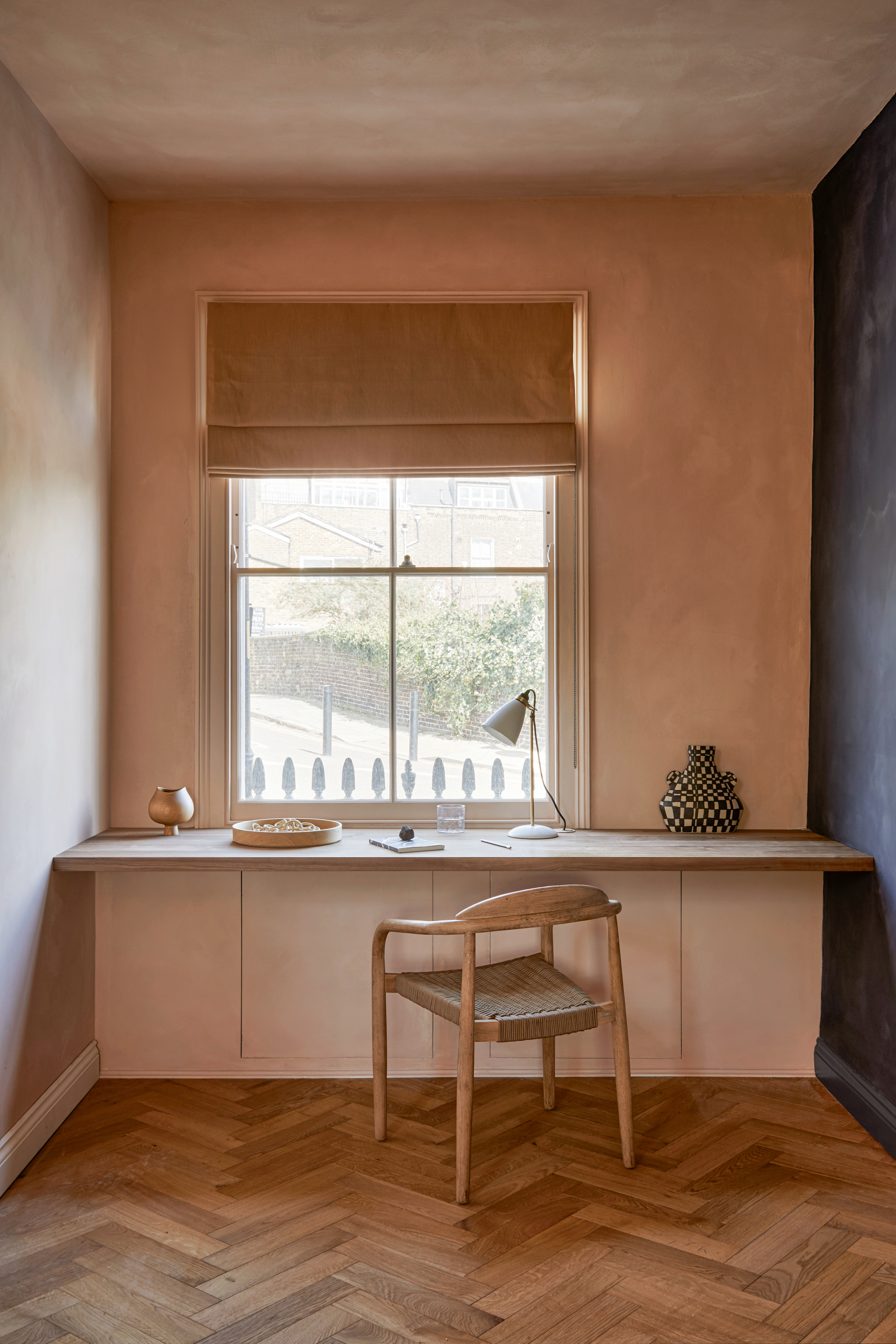 Desk area with built-in table against a plaster pink wall