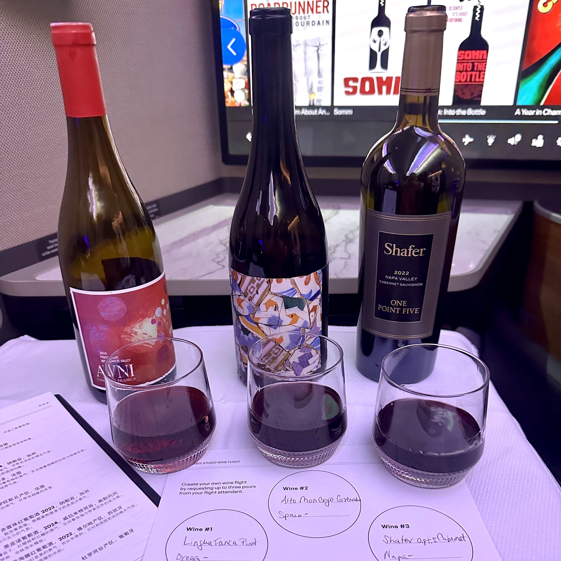 Three bottles and three glasses of red wine, including Shafter One Point Five, served with a tasting sheet to a business-class customer in United Airlines' Studio seats.