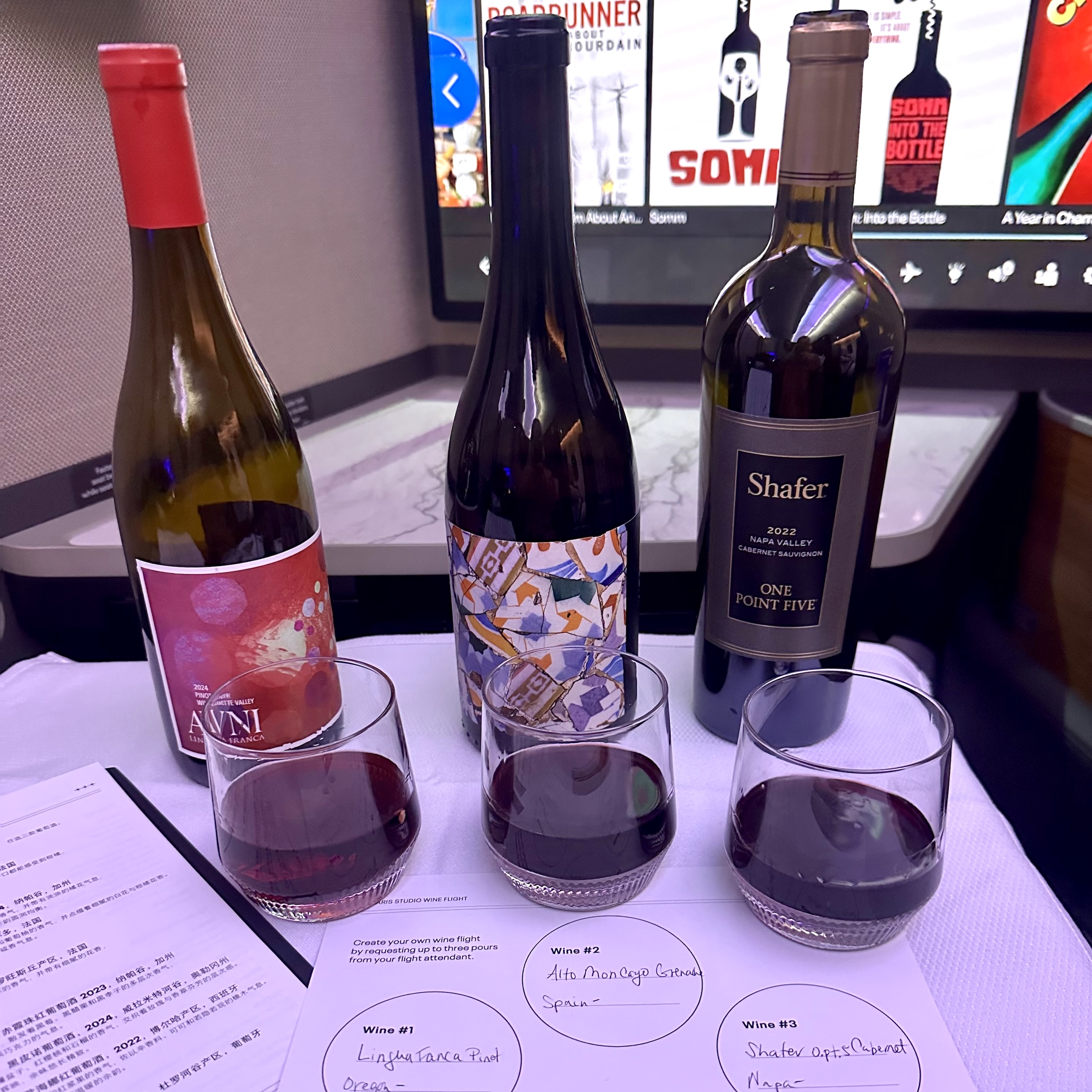 Three bottles and three glasses of red wine, including Shafter One Point Five, served with a tasting sheet to a business-class customer in United Airlines' Studio seats.
