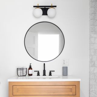 white bathroom and black mirror with walls wooden vanity with a few accessories on top