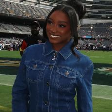 Simone Biles attended her husband's football game in the ultimate game day look: a denim skirt set, custom boots, and a Chanel bag