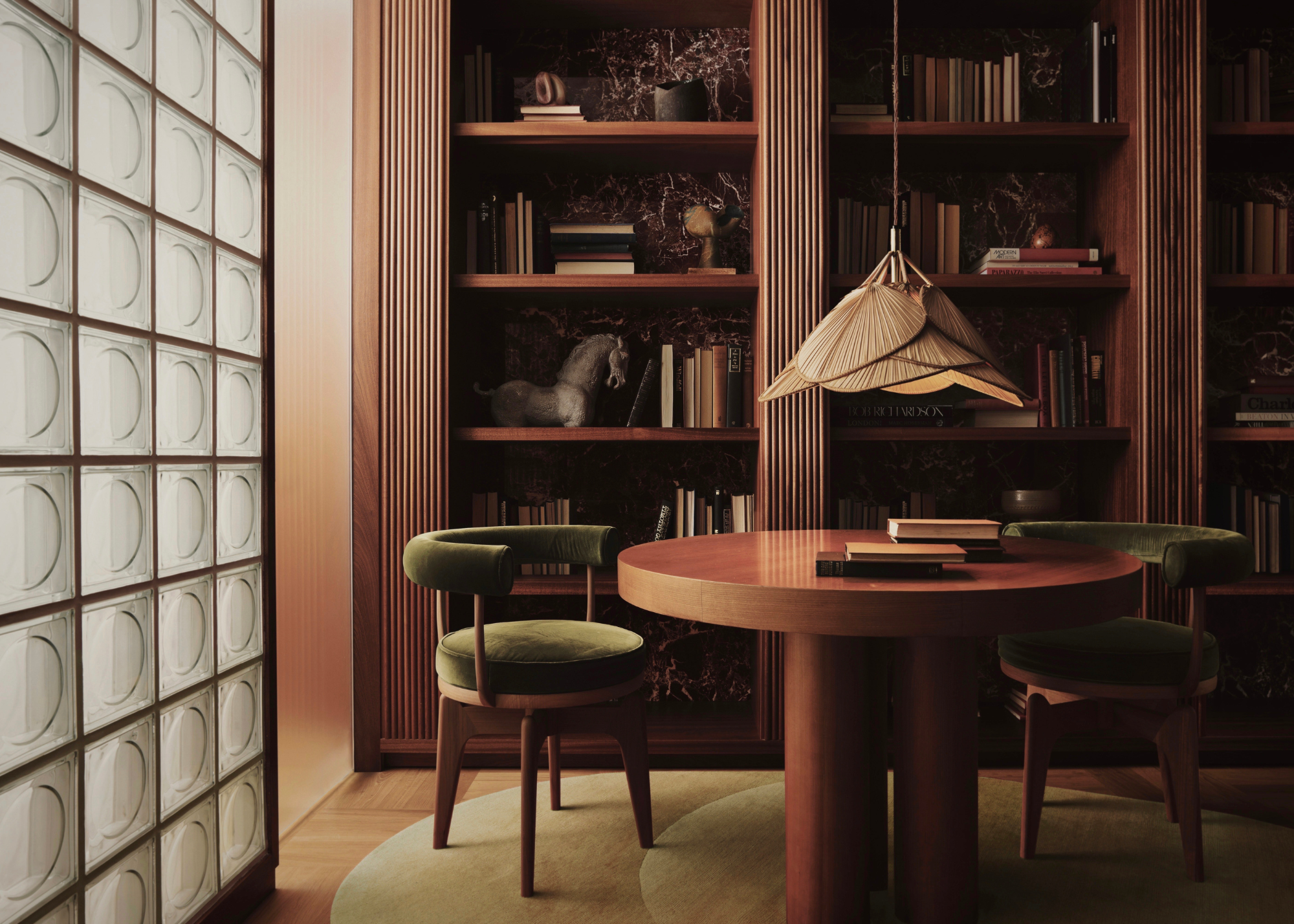 A contemporary space with a table and two chairs with bookshelfs behind and a glass brick wall with mood lighting and rug