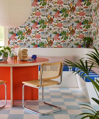 breakfast nook with wildlife colorful wallpaper, white corner bench with striped cushions, red round table with rattan dining chairs