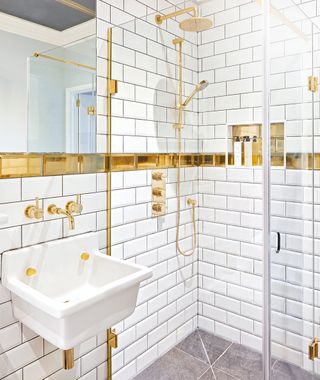bathroom with white wall tiles and gold accents with wah basin