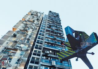 Daytime image of a tower block from the ground level up, balconies with satellite dishes and other attachments, airborne drone council monitor camera in shot, blue sky