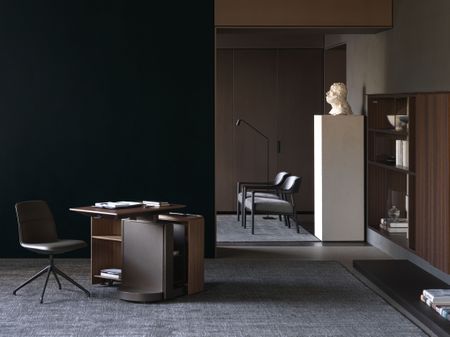 Home office desks by Studio Klass for Molteni, photographed in a dimly lit space with a marble bust and two chairs visible in the next room