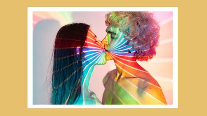 a couple kissing with a rainbow light on them, signifying a rainbow kiss
