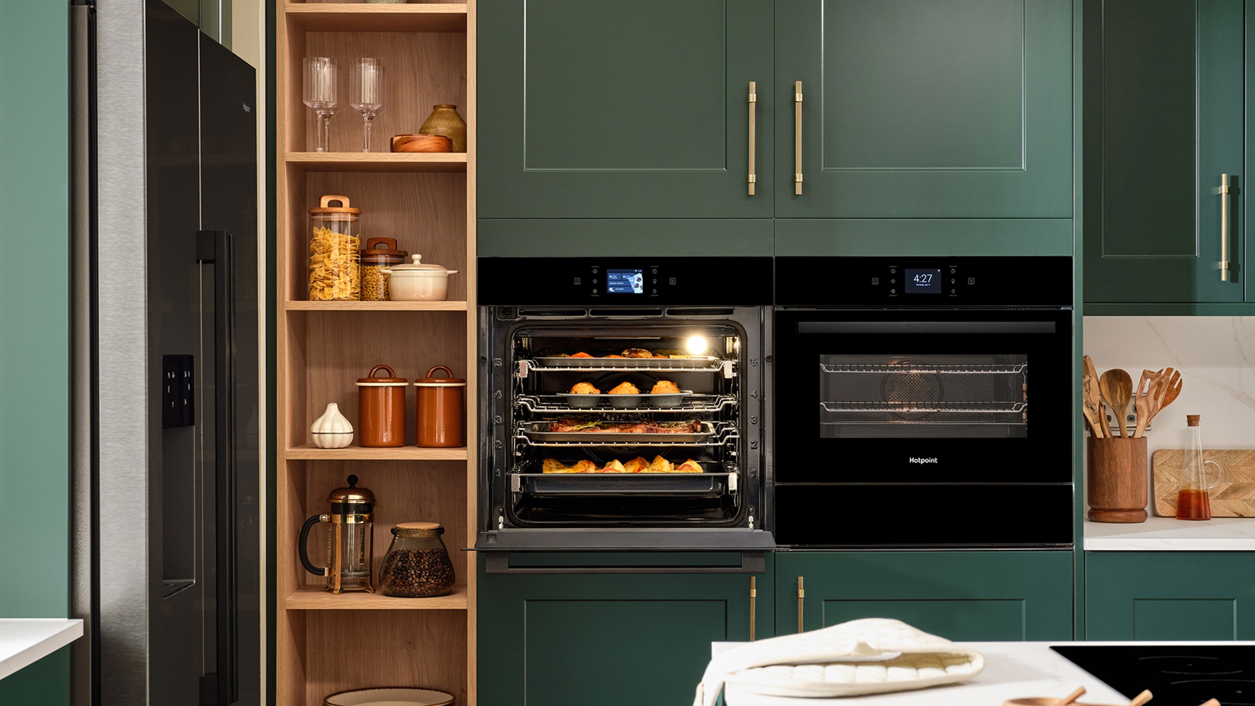 Kitchen with green cabinetry and double built-in ovens
