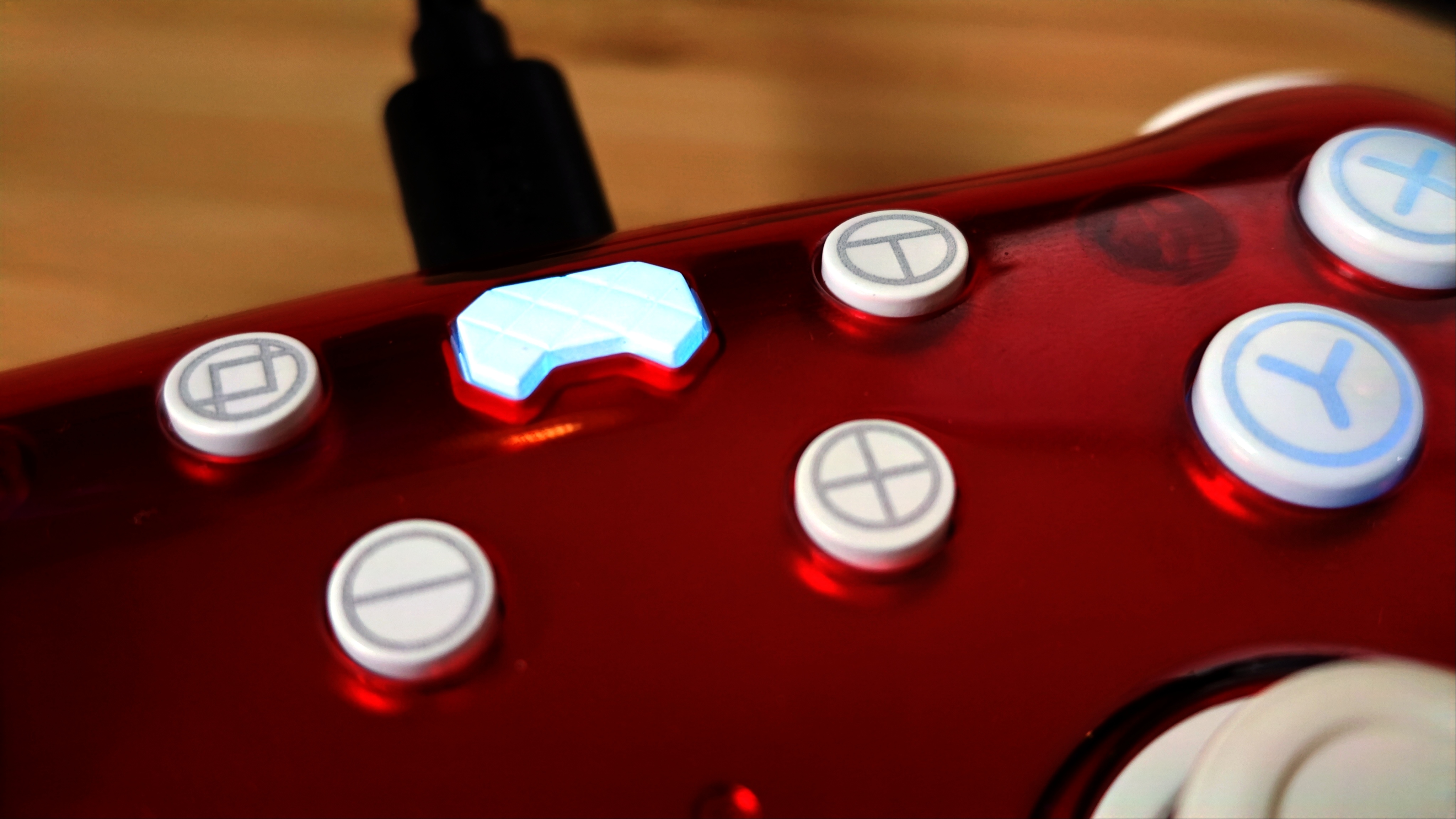 A Ruby red PB Tails gaming controller sitting on a wooden desk