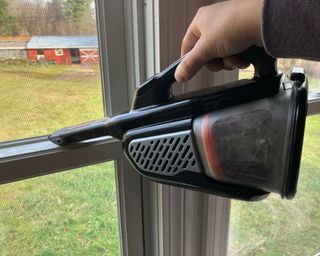 Contributing editor, Paige Cerulli cleaning windowsills using the Black + Decker dustbuster handheld vacuum crevice tool to remove cobwebs