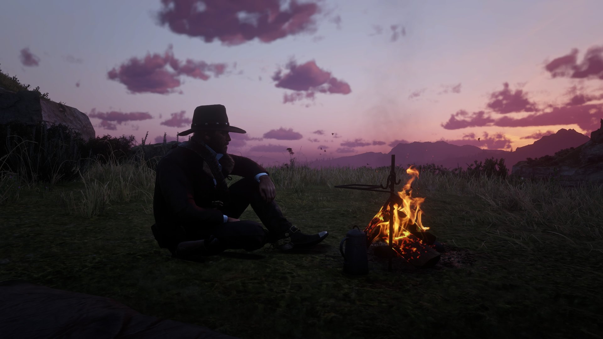 Red Dead Redemption 2 screenshot of Arthur Morgan sitting by a campfire against a purple-hued sunset
