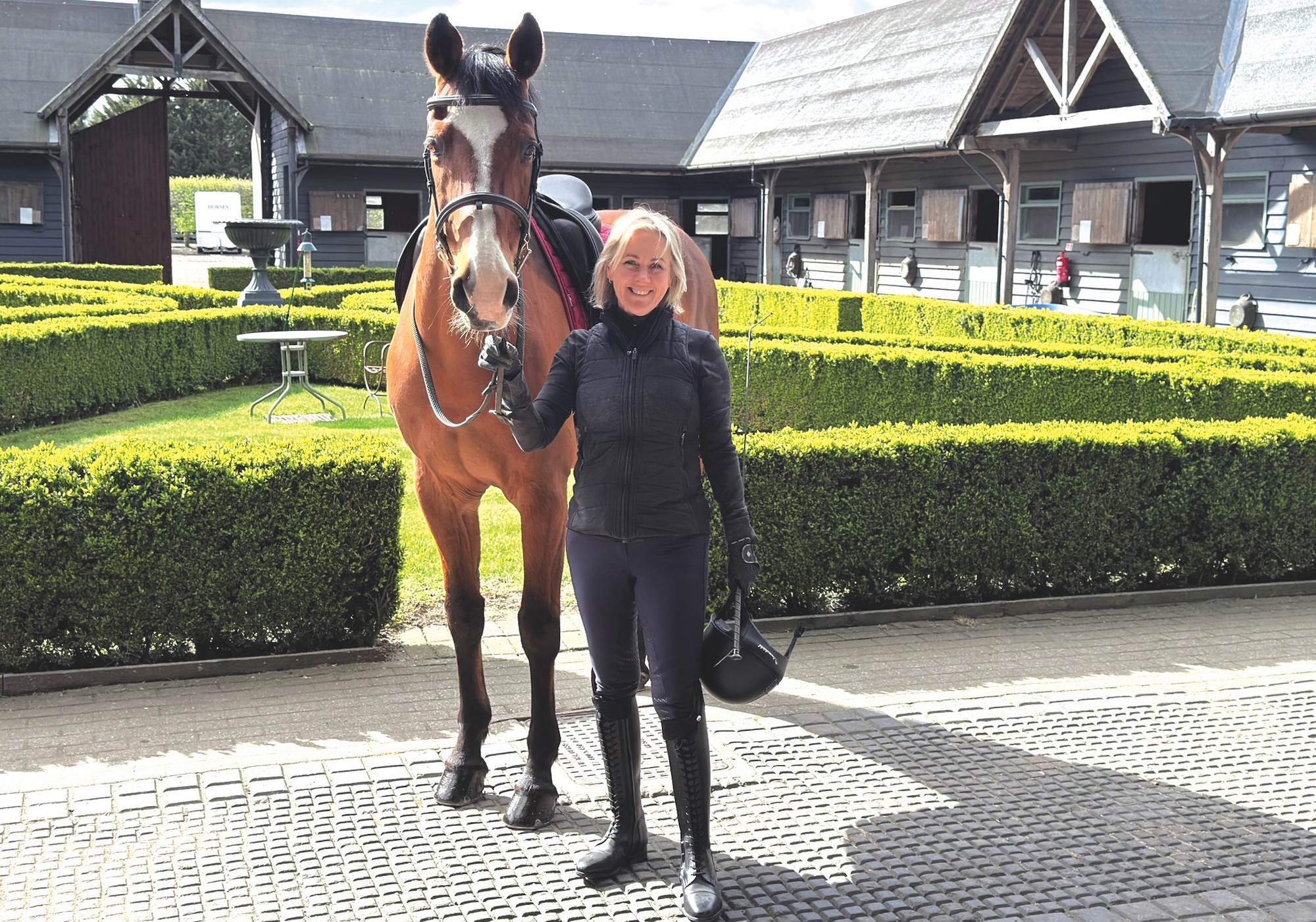 Writer Jojo Moyes standing with her horse Joey at a yard