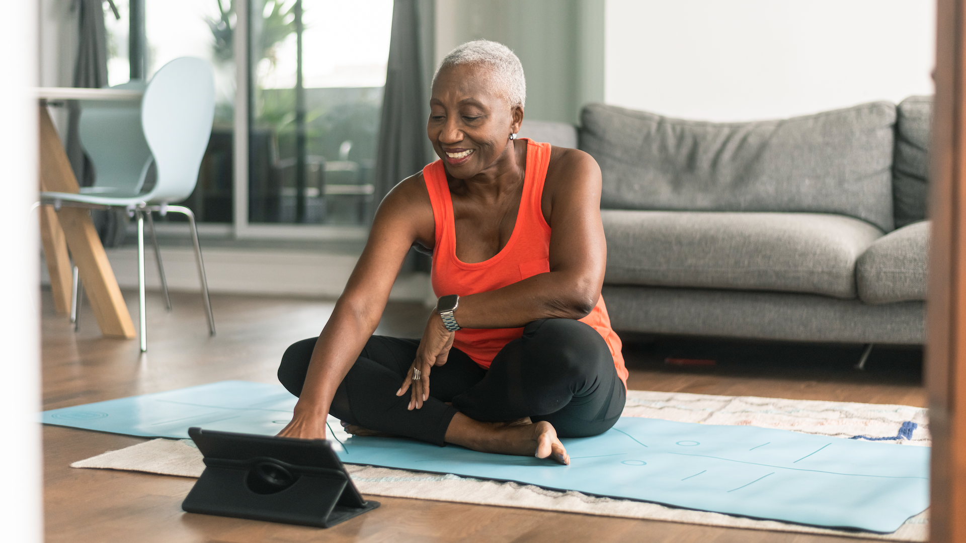 Woman sat on yoga mat while using tablet