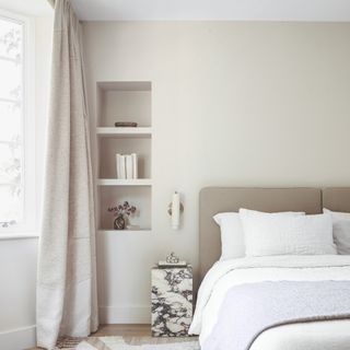 A neutral bedroom with a stone bedside table
