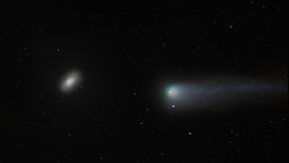 a comet on the right has a red/pink nucleus in the center and a glowing greeny blue coma which stretches out into a long tail to the right. The black eye galaxy shines bright but has a distinct dark patch covering one side of the galaxy center.