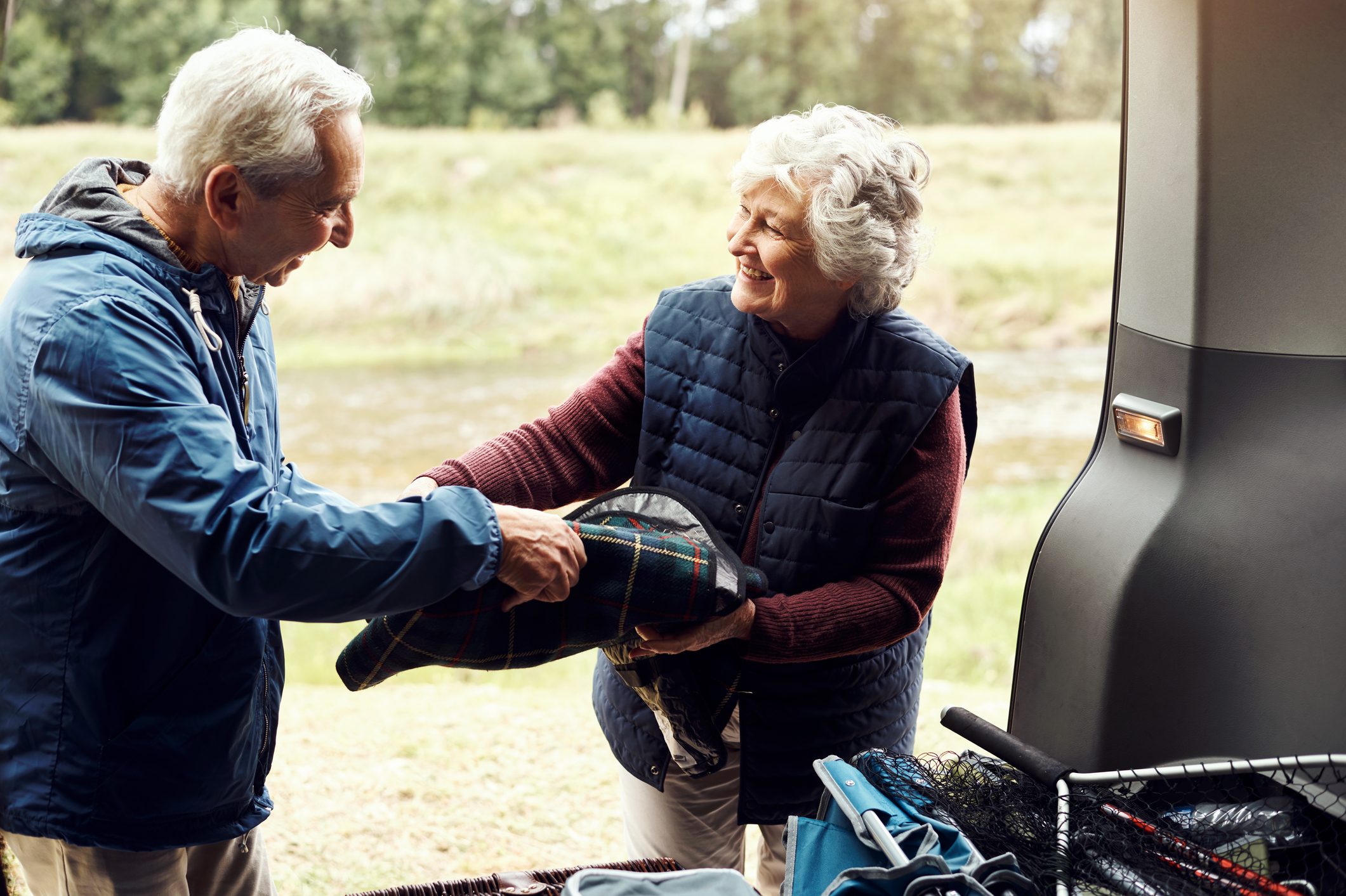 A smiling couple loading their car for a road trip