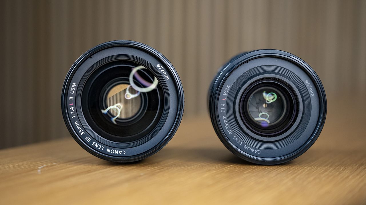 The Canon RF 35mm F1.4 lens on a wooden table alongside the Canon EF 35mm F1.4