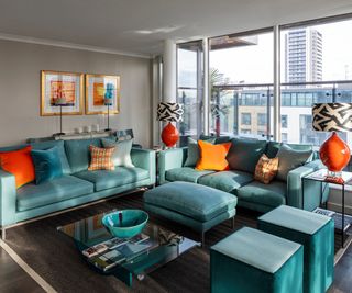appartment living room with teal sofas and orange accent cushions