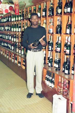 African male standing holding a bottle of wine in supermarket