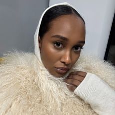 Mona taking a selfie wearing a fur shawl.