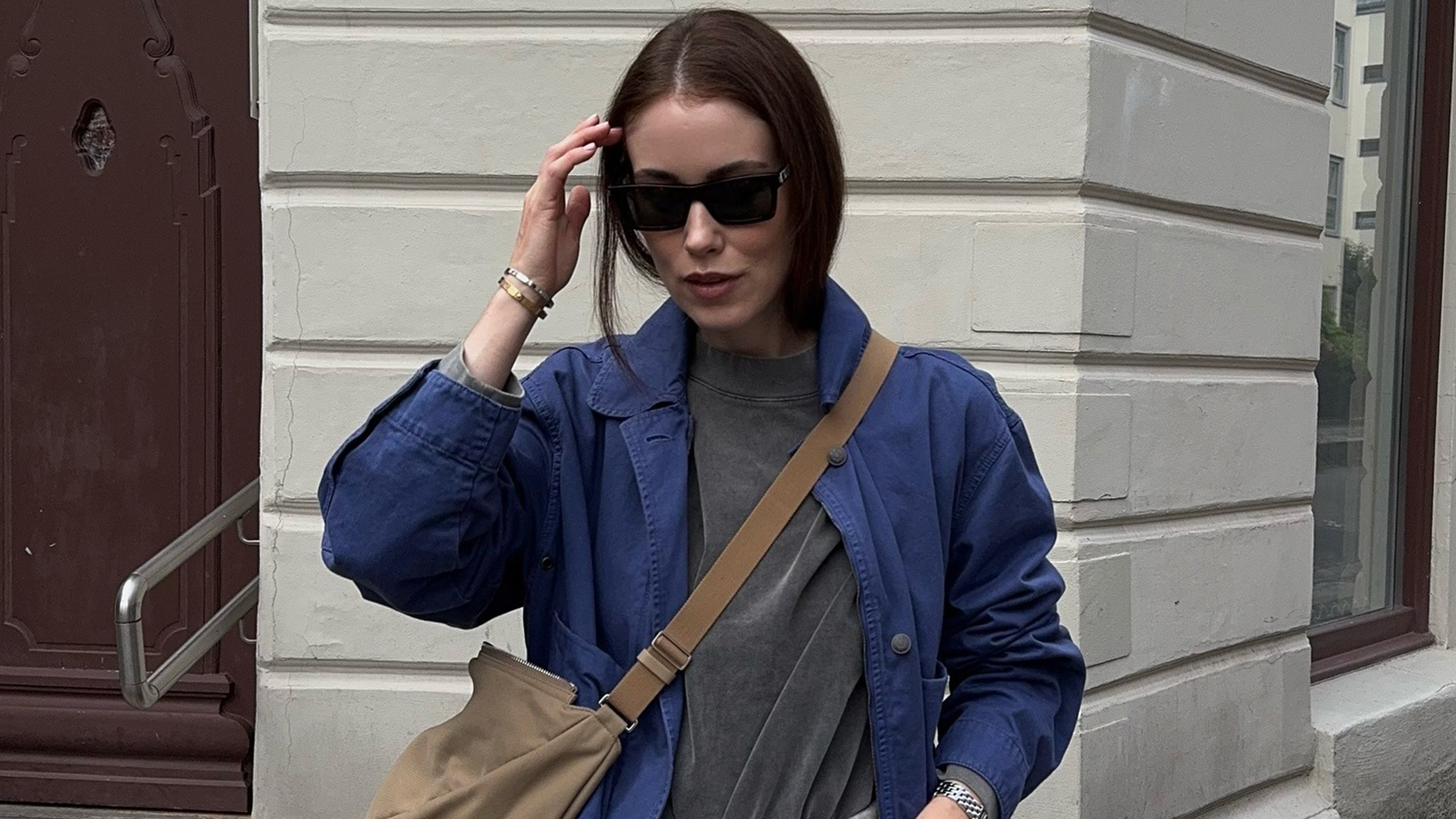 Annabel wears a blue jacket, gray t-shirt, and suede crossbody bag.