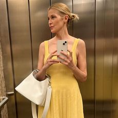 Kelly Rutherford wears a yellow dress, carries white handbag