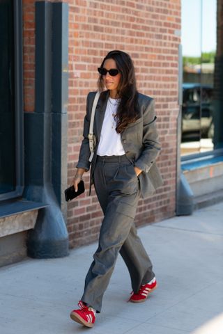 woman wearing blazer, t-shirt, trousers, and red adidas sambas