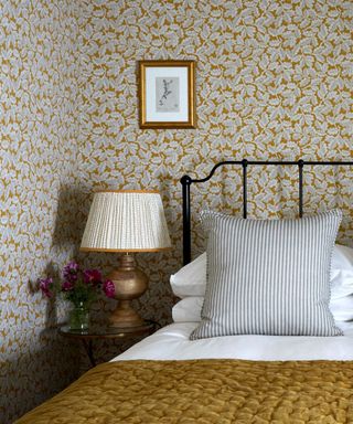 Bedroom with patterned wallpaper, lampshade and bedding
