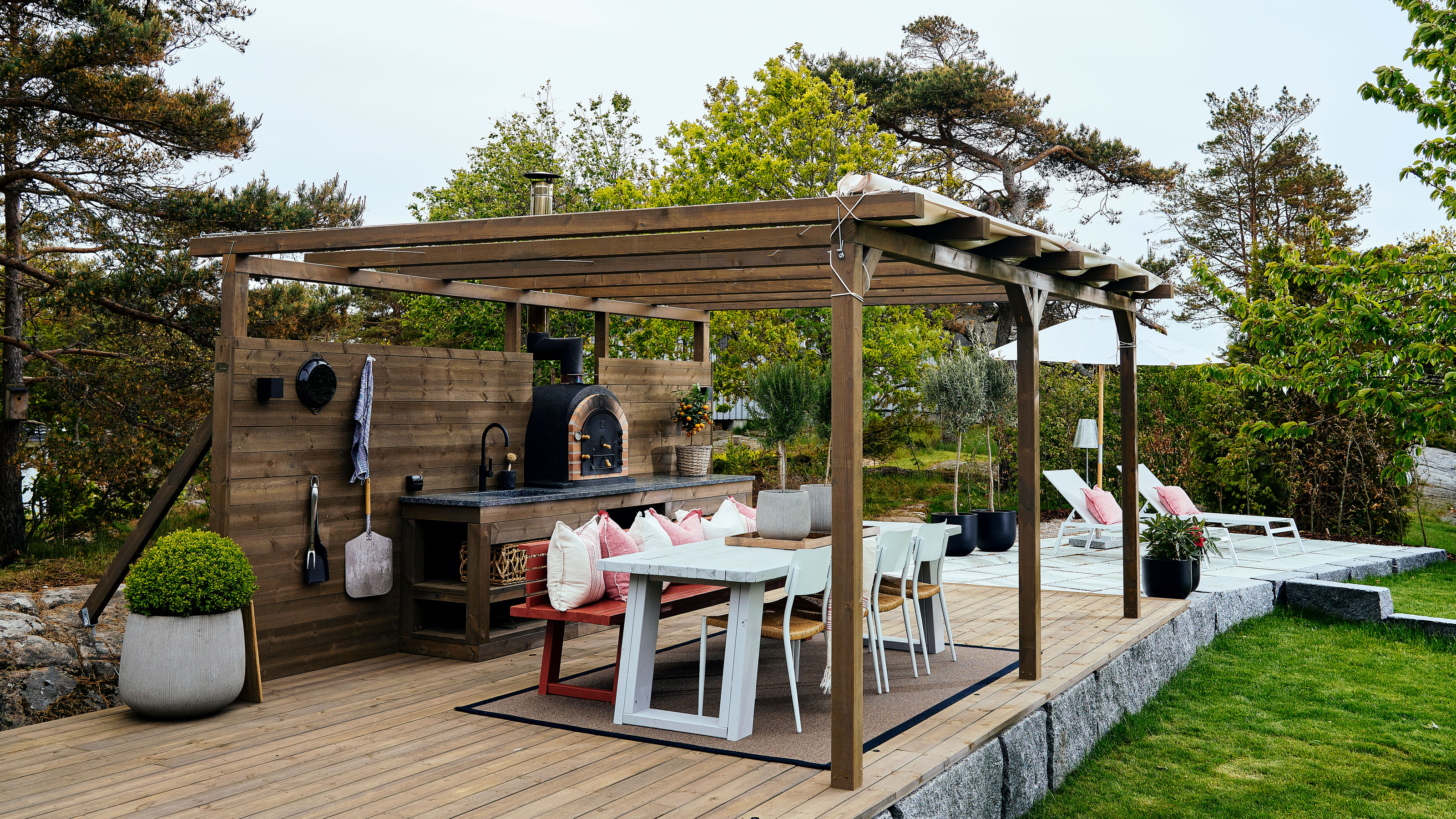 Outdoor kitchen with pizza oven, dining table and seats