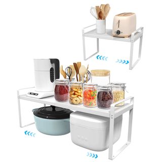 White metal shelf risers with a toaster, kettle, utensils, pots and glass pots of dried food