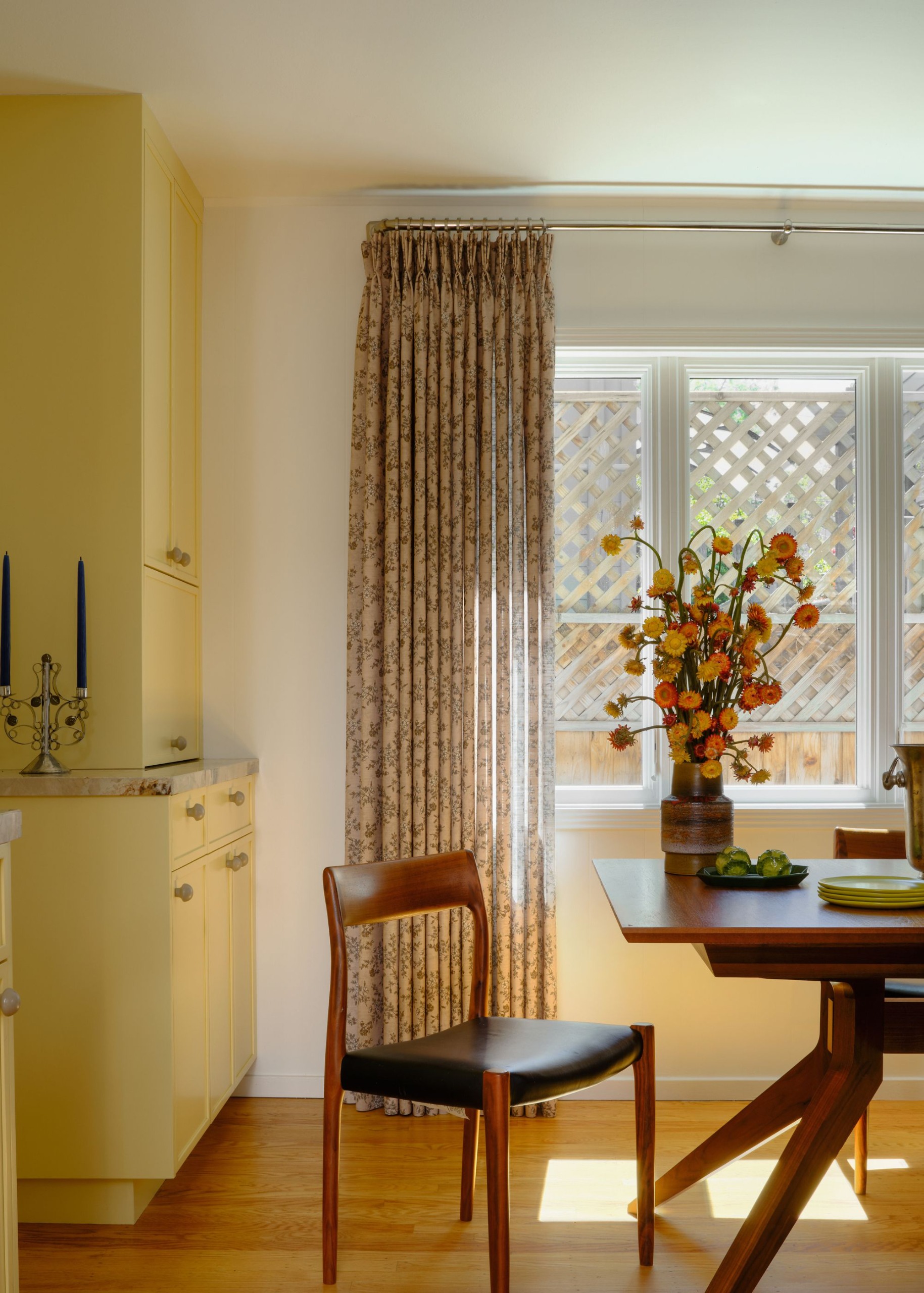 A dining room connected to the kitchen, with simple, clean-lined furniture and a large window welcoming in the sun