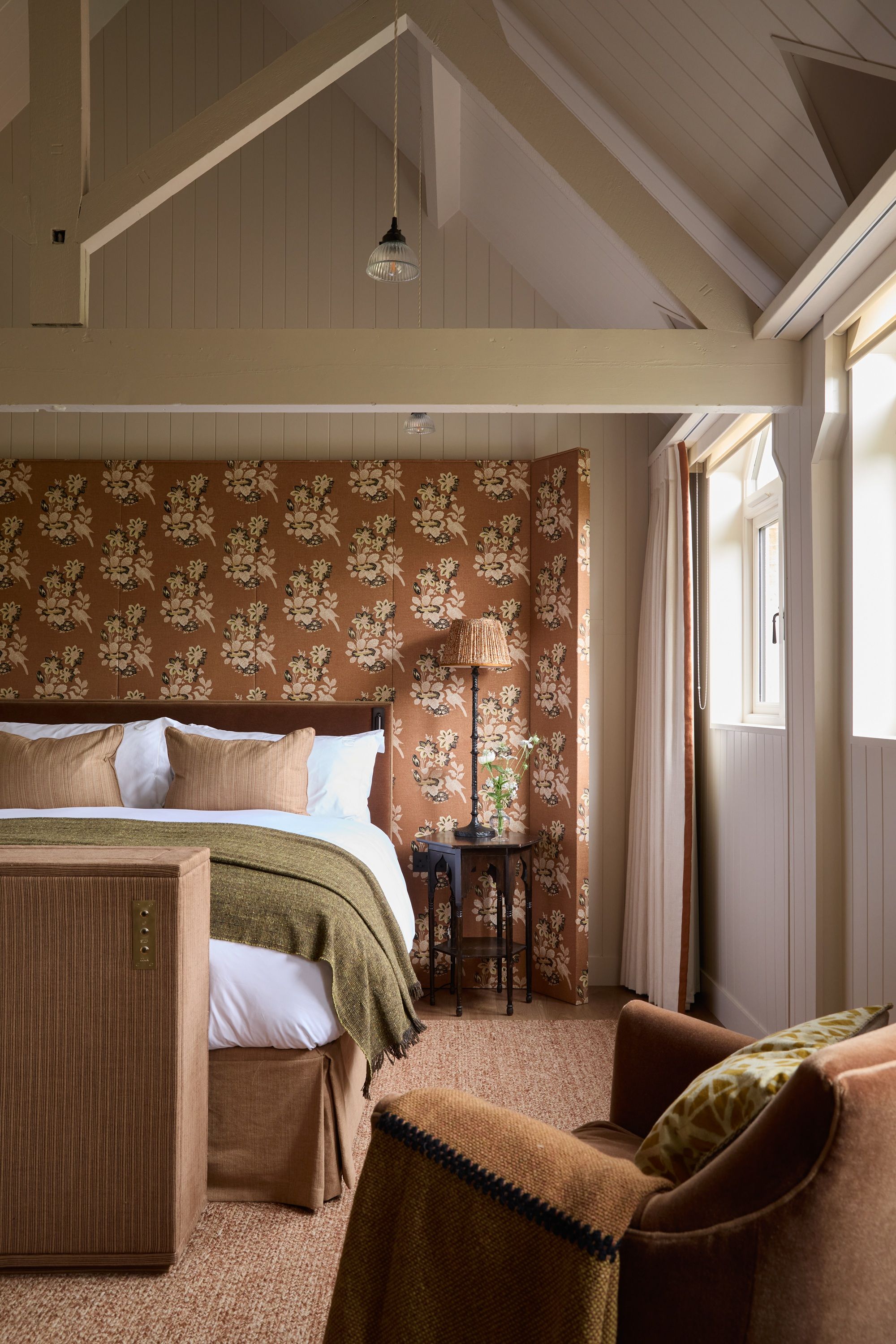 a bedroom with a pitched ceiling and large patterned headboard
