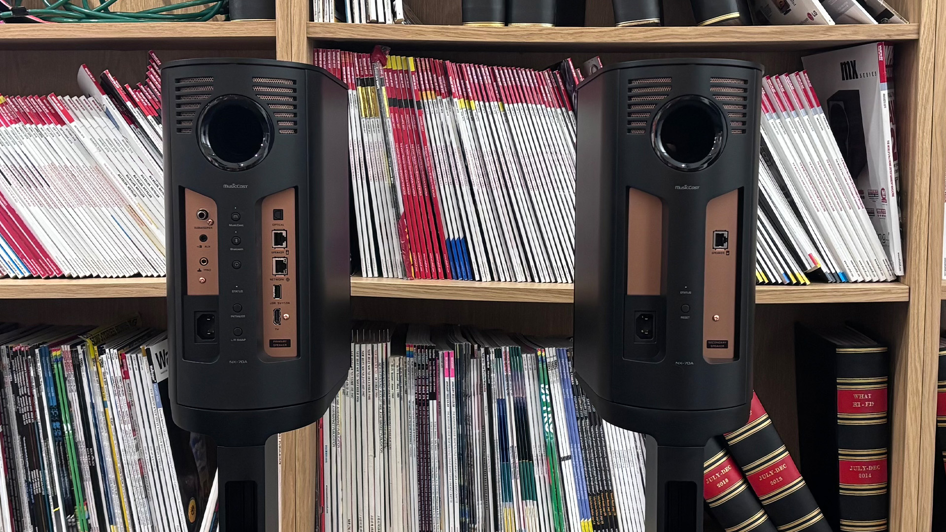 Yamaha NX-70A all-in-one system on stands in front of bookcase, showing rear of speakers