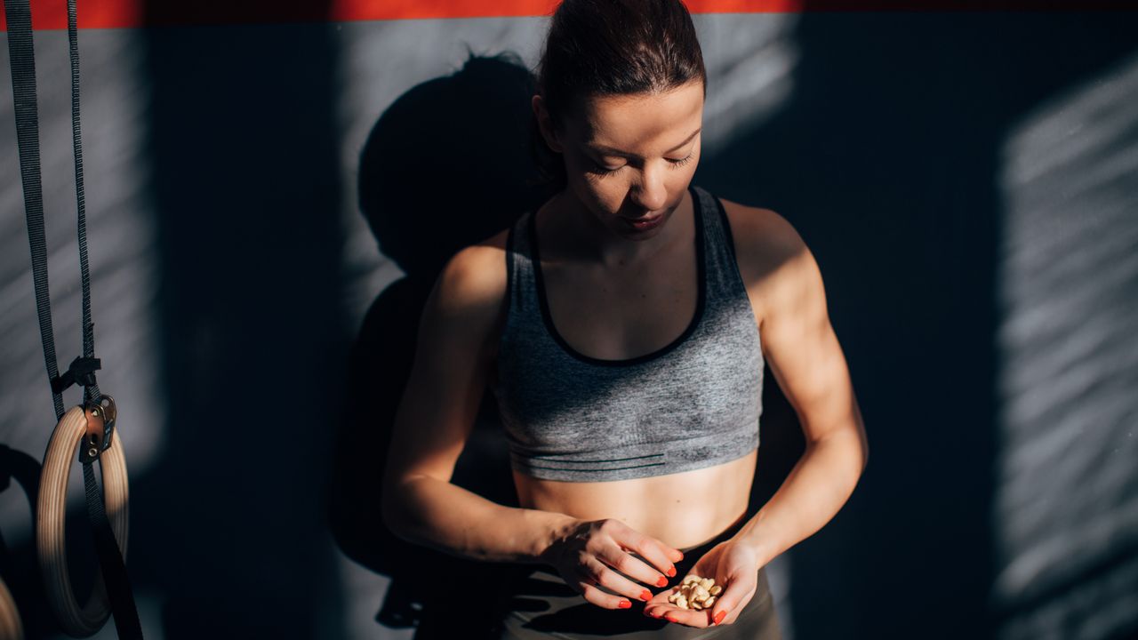 Woman in gym wear holding nuts in a cupped palm